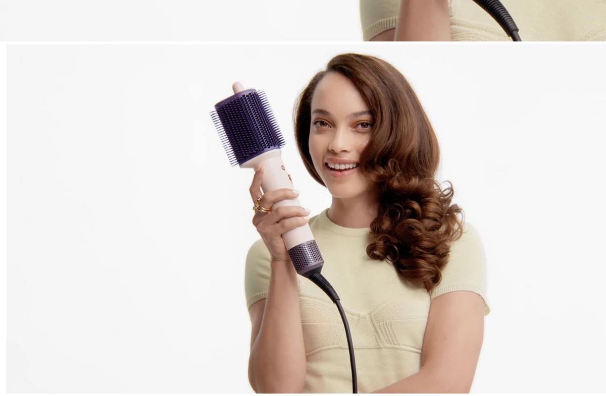 Модель держит фен-щётку Dyson Airsmooth
